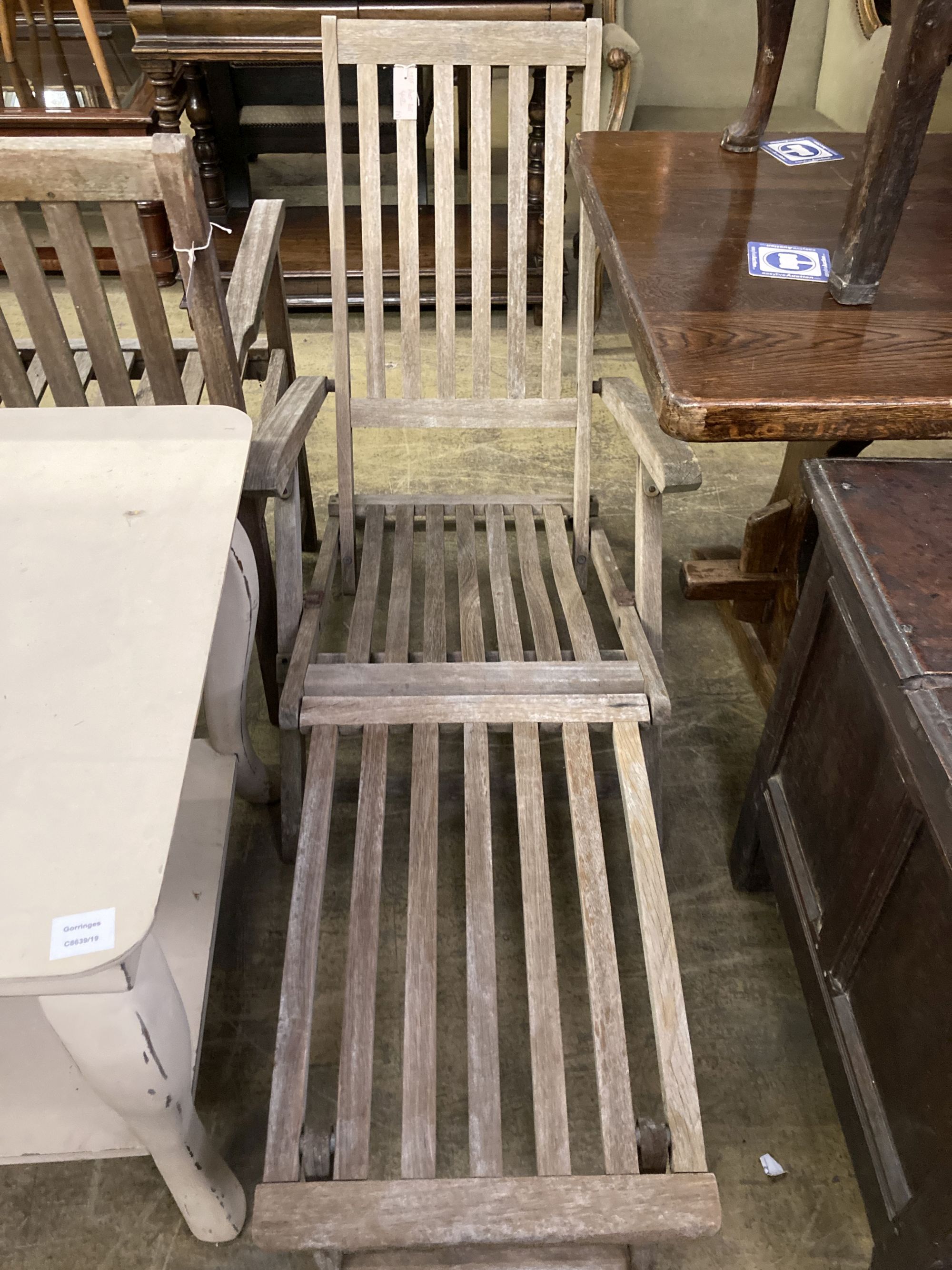 A weathered teak garden bench, length 129cm together with a teak steamer chair and nest of three teak rectangular garden tables